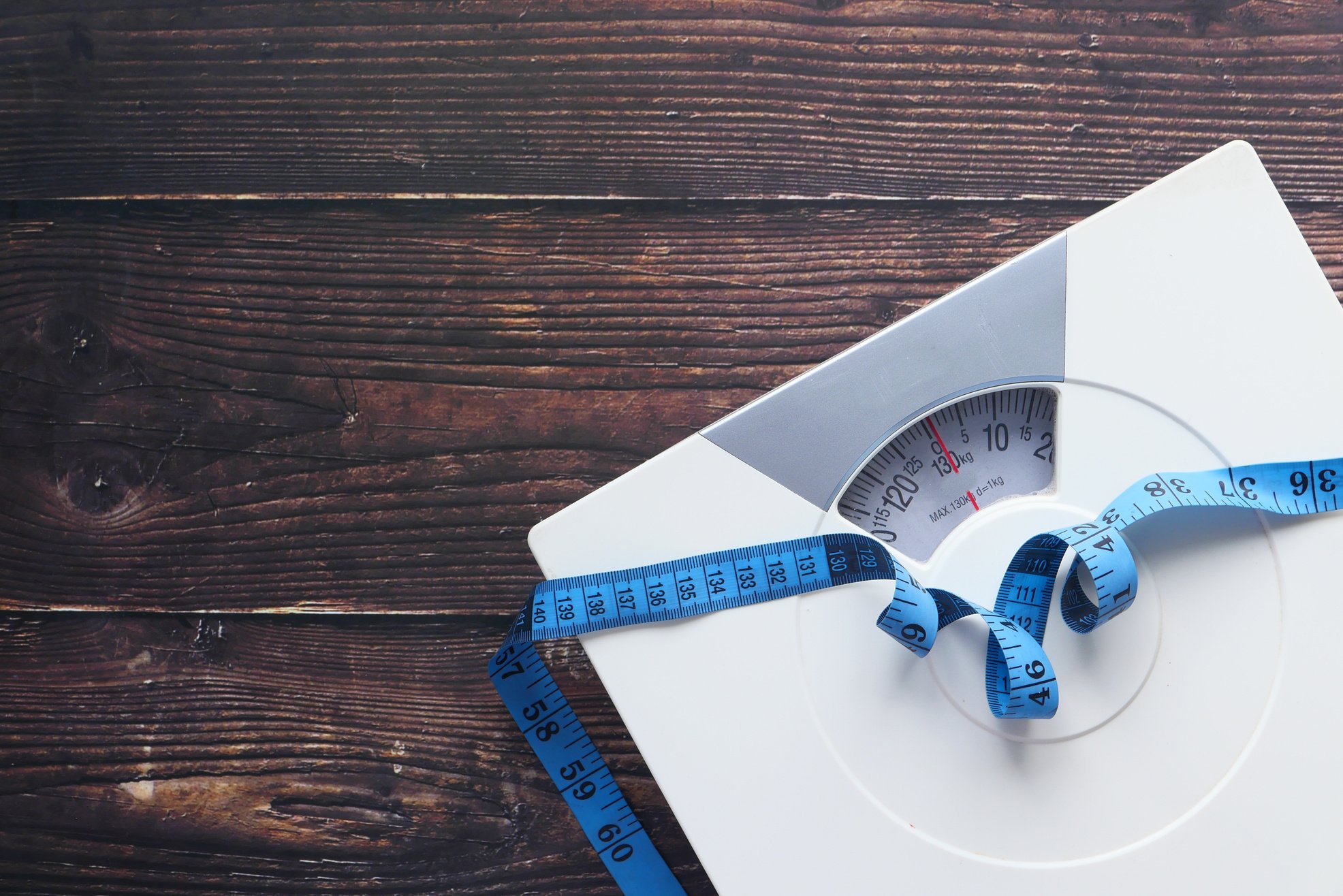 A Tape Measure and Bathroom Scale on Wooden Floor.